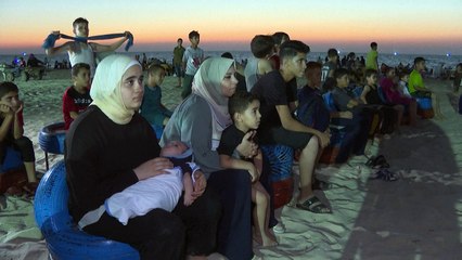 Palestinos se refrescam no "Cinema do Mar" na praia de Gaza