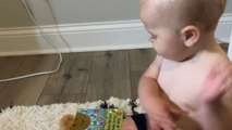 Cute little baby wants his mother to read him his favourite book by pointing at the pages