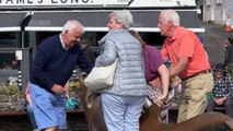 Elderly woman draws audience around her from her laughing fit while trying to get off a statue