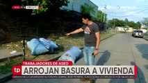 Trabajadores de aseo arrojan basura en la acera de una vivienda en Santa Cruz