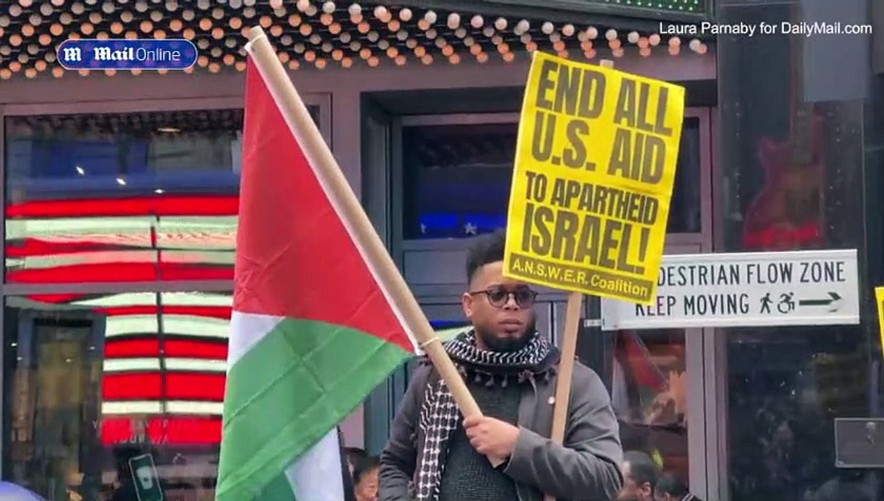 Fury as Palestinian protester waves a SWASTIKA at anti-Israel rally in New York City's Times Square as thousands of demonstrators take to the streets across the US - while rockets and gunfire flies in the Middle East