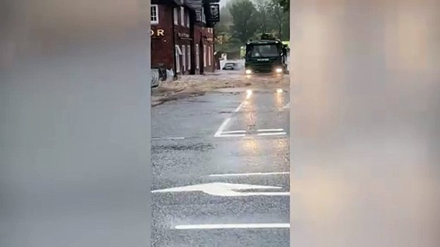 Lorry drives through a flood pushing excess water into a pub as Storm Babet hits.