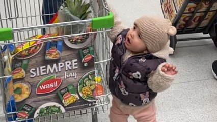 Toddler adds his favorite treats in shopping cart while dad's on phone