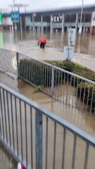 Un cycliste tente de traverser un parking inondé