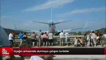 Uçağın arkasında durmaya çalışan turistler