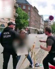 The policeman enjoys the party of tearing and burning the Qur’an and helps the clowns