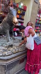 Une femme ramasse une pièce de monnaie qui vient d'être jetée dans la fontaine