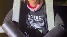 Environmentalist Dr Lisa Searle attaches herself to the gate of the main access road leading to the NSW Forestry Corporation's headquarters in Pennant Hills