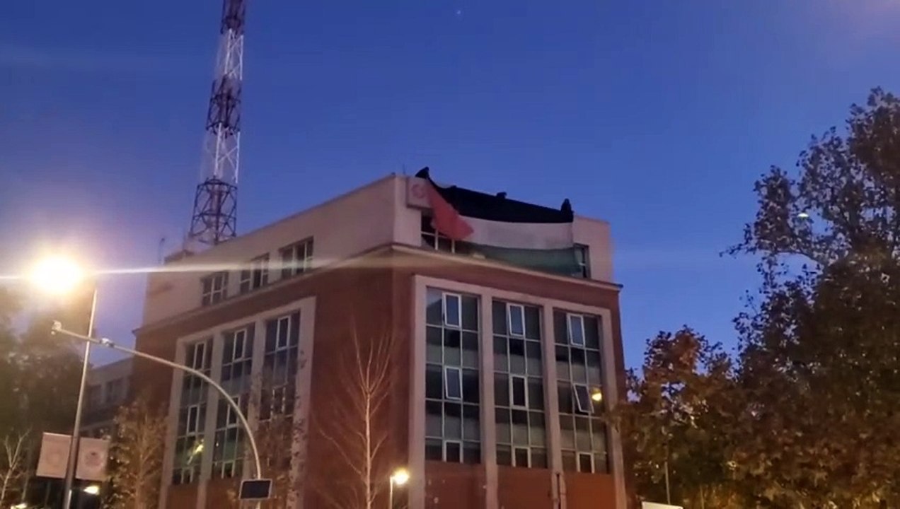 Varios activistas despliegan una bandera de Palestina frente a la sede de Israel en Madrid