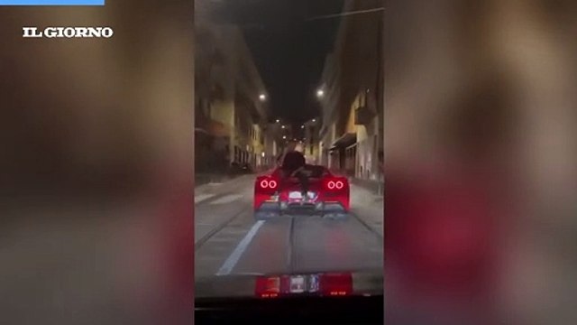 Follia a Milano, parla al telefono seduto sul cofano di una Ferrari in movimento