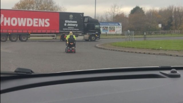 Carefree elderly gentleman zooms around a roundabout on his mobility scooter