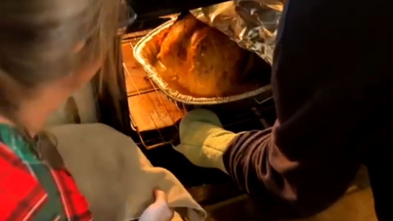 Excited couple feels the heat while taking Thanksgiving turkey out of oven