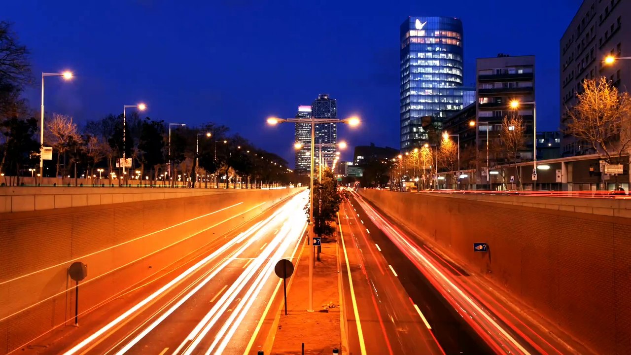 Time lapse of traffic in an underground tunnels in a city with tall buildings at night.