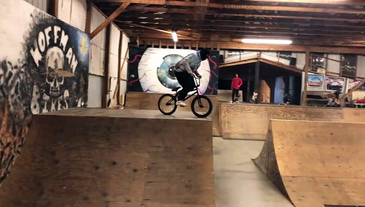 BMX rider jumps off top of half pipe at skatepark and faceplants