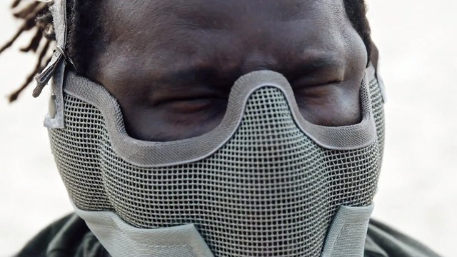 Black Polish Man Wearing A Gray Airsoft Wire Mesh Half Mask Showing An Angry Face While Shaking His Head