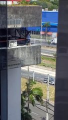 Mulher entra em situação de risco para limpar janela de prédio