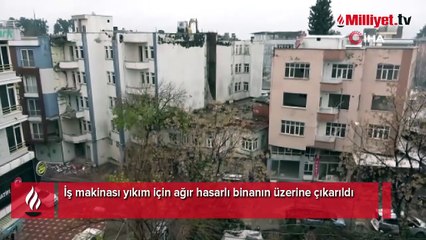 İş makinası yıkım için ağır hasarlı binanın üzerine çıkarıldı