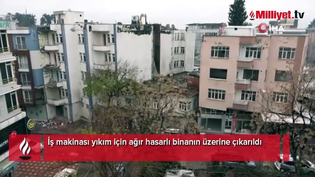 İş makinası yıkım için ağır hasarlı binanın üzerine çıkarıldı