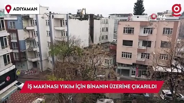 İş makinası yıkım için ağır hasarlı binanın üzerine çıkarıldı