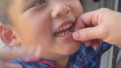 Wobbly farewell: Little boy grins as his first tooth takes flight