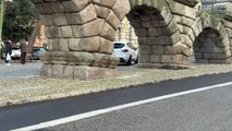 Un coche se salta un bordillo para cruzar por debajo del Acueducto