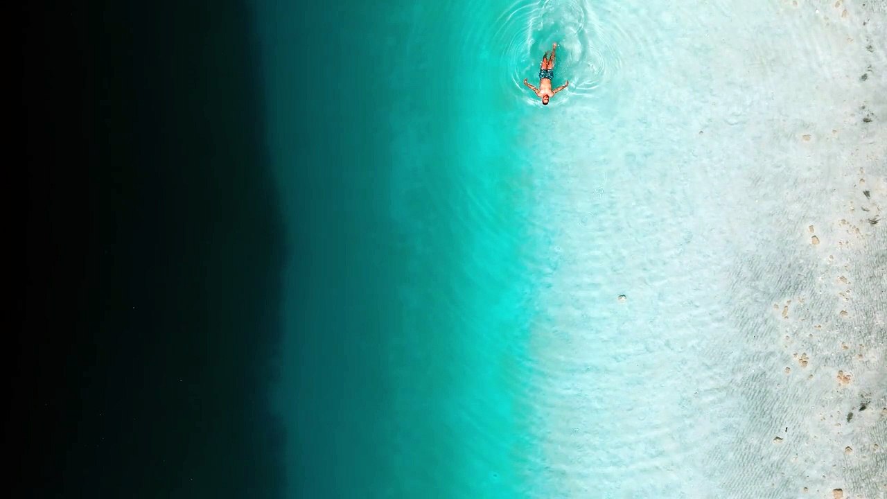 Man swimming in ocean water aerial shot