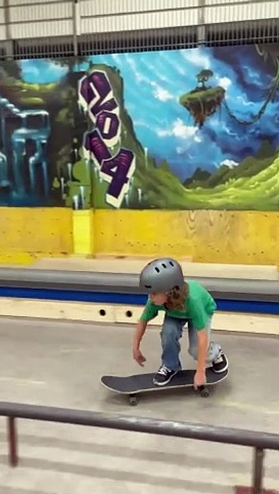Boy on skateboard attempts 50-50 grind on rail at skatepark and lands on his arm