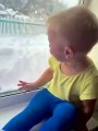 El niño se ríe histéricamente mientras su padre arroja nieve a la ventana.