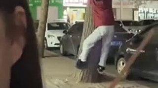 男子晚上喝醉酒爬樹，妻子淡定拍攝視頻記錄。A drunk man climbs a tree while his wife shoots video.