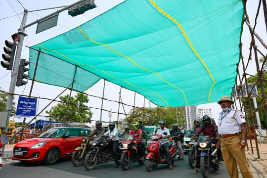 कोयम्बत्तूर में रेड लाइट पर दुपहिया वाहन सवारों को झुलसाती गर्मी से बचा रहा ग्रीन शेड