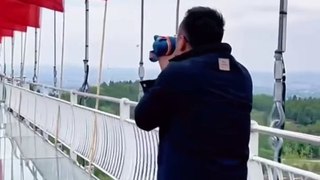 男子害怕過玻璃橋，用杯子擋住視線。Man was afraid of crossing the glass bridge and blocked his view with cup.
