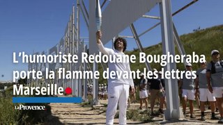 L’humoriste Redouane Bougheraba porte la flamme devant les lettres Marseille