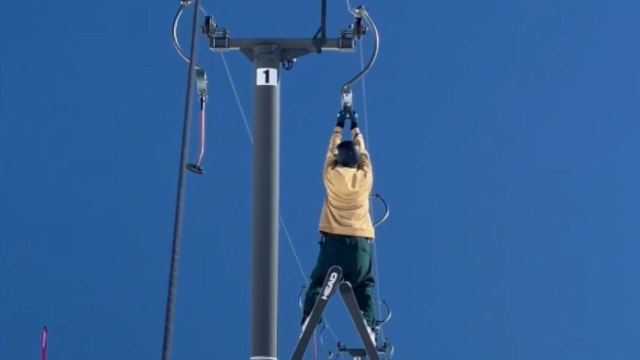 Fearless skier defies convention by hanging from a soaring lift