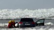 Los bomberos sacan del mar un coche encallado en la playa de Oyambre mientras sus ocupantes se van al chiringuito