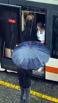 Eskişehirli kadın esnaf, makas değiştirmek için tramvaydan inen vatmanın ıslanmaması için şemsiye tuttu