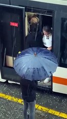 Eskişehirli kadın esnaf, makas değiştirmek için tramvaydan inen vatmanın ıslanmaması için şemsiye tuttu