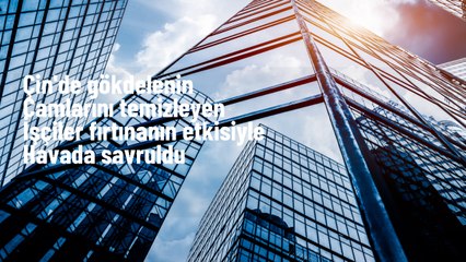 Pekin'deki gökdelenin camlarını temizleyen işçiler fırtınada havada savruldu