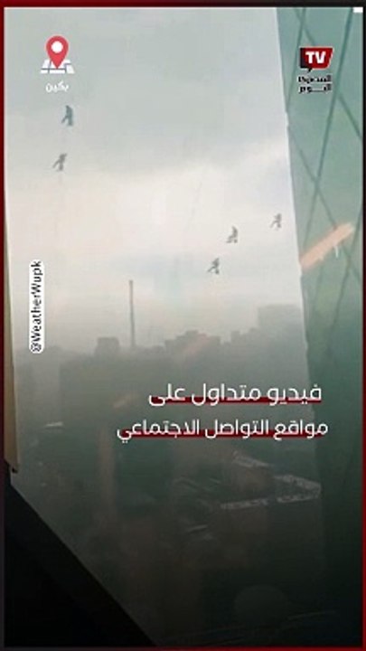 العاصفة تطيح بعمال تنظيف بعيدًا عن مبني شاهق في بكين