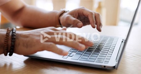 Hands typing email on laptop at desk in house