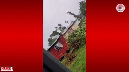 En Jamaica, una mujer se aferra al techo de su casa, para que el huracán Beryl no se lo lleve