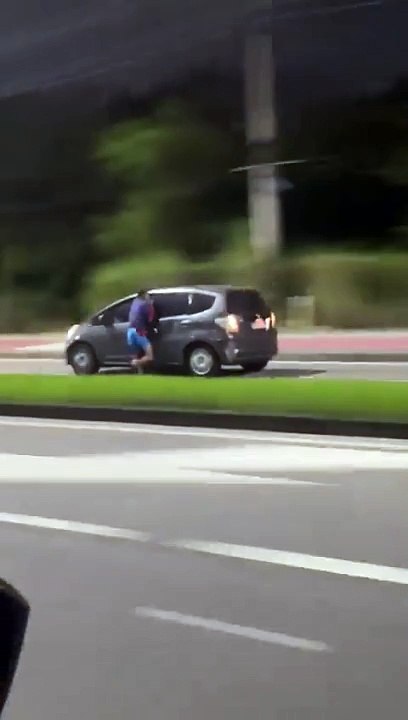 Suspeito de assalto fica pendurado a janela de carro em movimento