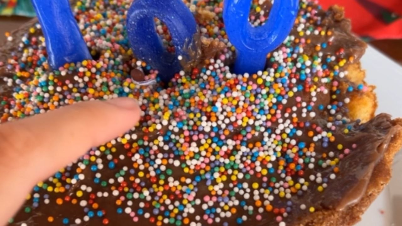 Girl hands clueless dad a birthday cake with a firecracker hidden as a candle