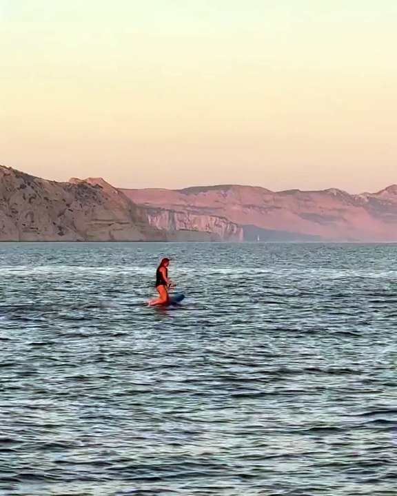 Assise à genou sur une planche en train de faire du knee board, l'interprète du titre Je vole réussit à surfer sur la mer comme on le découvre dans une vidéoLouane en vacances dans le Sud, instagram, août 2024.
