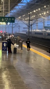The railway station is drenched with heavy rain and strong winds, causing luggage to roll across the slipp...and relentless downpour make for a challenging and chaotic scene as travelers struggle to stay steady and manage their bel