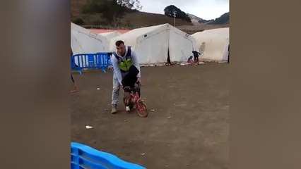 Un policía ayuda a un niño migrante a andar en bicicleta por primera vez