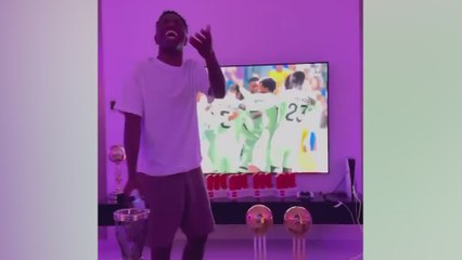 Vinicius casually games in a living room flooded with trophies