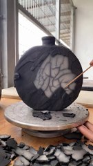 Artist is peeling the coating off of a vase after the secondary firing to reveal a beautif