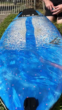 Surfer is scraping old wax off of his surfboard!