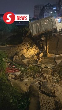 Prolonged heavy rain causes riverbank to collapse, damaging two vehicles