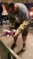 Glass artist is placing the head onto the glass bear he is making!